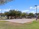 A community volleyball court with a sand surface, covered picnic area, and lush green surroundings on a sunny day at 18848 N Barano Dr, Maricopa, AZ 85138