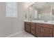 A bathroom featuring double sinks, brown wood cabinets, a tile floor, and a framed mirror at 1931 E Lantana Dr, Chandler, AZ 85286