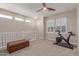 Bright bonus room featuring carpet, a ceiling fan, staircase, bench, and exercise bike for comfortable workout at 1931 E Lantana Dr, Chandler, AZ 85286