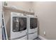 Bright laundry room featuring washer and dryer, shelving, tile flooring, and a doorway at 1931 E Lantana Dr, Chandler, AZ 85286