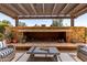 A cozy covered patio with an outdoor fireplace, comfortable seating, tile flooring, and lush greenery at 1931 E Lantana Dr, Chandler, AZ 85286