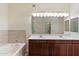 Bathroom featuring double sinks, a soaking tub with tile surround, and good lighting at 19700 N 76Th St # 2169, Scottsdale, AZ 85255