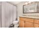 Bathroom with a shower curtain, wood-look cabinets, granite countertops, and a large mirror at 19777 N 76Th St # 1131, Scottsdale, AZ 85255
