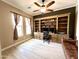 Spacious office with a large built-in bookshelf, neutral walls, ceiling fan, and ample natural light at 20525 W Hamilton St, Buckeye, AZ 85396