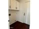 Well-lit laundry room with white cabinets, dark hardware, and hardwood floors at 2074 N 109Th N Ave, Avondale, AZ 85392
