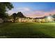 Vast backyard featuring lush green lawn, warm lighting, and a spacious patio area at 2106 E La Vieve Ln, Tempe, AZ 85284