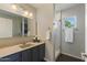 Well-lit bathroom featuring a modern vanity, mirror, lighting fixtures, and tiled walk-in shower with glass doors at 2106 E La Vieve Ln, Tempe, AZ 85284