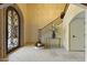 Elegant foyer with stone floors, staircase, console table with floral arrangement, and iron detailed entry door at 2106 E La Vieve Ln, Tempe, AZ 85284