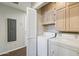Efficient laundry room with a side-by-side washer and dryer, overhead cabinets and convenient bi-fold door entry at 2106 E La Vieve Ln, Tempe, AZ 85284