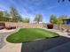 Landscaped backyard with artificial grass, decorative rock, and mature trees at 2348 W Alta Vista Rd, Phoenix, AZ 85041