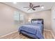 Comfortable bedroom with a ceiling fan, wood-look flooring, and a large window for natural light at 2425 E Flintlock Dr, Gilbert, AZ 85298