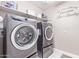 Modern laundry room with gray front-load washer and dryer and shelving at 2425 E Flintlock Dr, Gilbert, AZ 85298