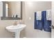 Charming powder room featuring pedestal sink, framed mirror, and towel rack, adds a touch of elegance at 2425 E Flintlock Dr, Gilbert, AZ 85298