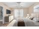 Comfortable bedroom featuring wood-style tile flooring, a ceiling fan, TV and open bathroom with shower at 2701 S Southwind Dr, Gilbert, AZ 85295