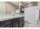 Well-lit bathroom with vanity, large mirror, and shower with white curtain at 2792 N Acacia Way, Buckeye, AZ 85396