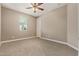 Neutral bedroom featuring a ceiling fan, window, and neutral carpet at 2792 N Acacia Way, Buckeye, AZ 85396