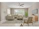 Modern, neutral living room with ample seating, a ceiling fan, and large windows for natural light at 2792 N Acacia Way, Buckeye, AZ 85396