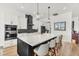 Contemporary kitchen boasts a large island with seating, sleek black and white cabinetry, and modern lighting fixtures at 35280 N Bell Rd, Queen Creek, AZ 85144