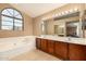 Bright bathroom featuring dual sinks, large mirror, soaking tub and arch window at 4212 W Jason Dr, Glendale, AZ 85308