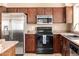 Bright kitchen boasts stainless steel refrigerator, black range, microwave, and dark wood cabinets at 4212 W Jason Dr, Glendale, AZ 85308