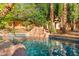 Inviting backyard pool featuring a charming rock waterfall, mature palm trees, and sparkling blue water at 4223 N St Elias --, Mesa, AZ 85215