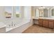 Bathroom featuring a soaking tub with tile surround and a vanity with lots of cabinets at 5557 W Mine Trl, Phoenix, AZ 85083