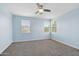 A cozy bedroom featuring two windows, carpeted floors, and ceiling fan at 5557 W Mine Trl, Phoenix, AZ 85083