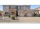Two-story home with stone accents, a paver driveway, a two-car garage, and a desert-landscaped front yard at 5557 W Mine Trl, Phoenix, AZ 85083