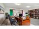 Bright home office with wooden desk, bookshelf, and comfortable black chair with a view to the upstairs landing at 5557 W Mine Trl, Phoenix, AZ 85083