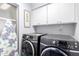 Functional laundry room equipped with a washer, a dryer and storage cabinets at 7252 E Edgewood Ave, Mesa, AZ 85208