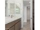 Bright bathroom features double mirrors and brown cabinets with white countertop and gray wood-look tile flooring at 7342 W Hedge Hog Pl, Peoria, AZ 85383