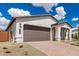 A wide view of a one-story house featuring a two-car garage and low desert landscaping at 7342 W Hedge Hog Pl, Peoria, AZ 85383