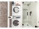 Bathroom showcasing a shower with glass doors and a stacked Electrolux washer/dryer appliance at 7740 E Heatherbrae Ave # 13, Scottsdale, AZ 85251