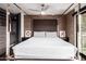 Bedroom boasts a four-post bed, brick accent wall, fan, and views of the outdoor balcony at 7740 E Heatherbrae Ave # 13, Scottsdale, AZ 85251