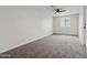 Spacious bedroom featuring neutral carpeting, a ceiling fan, and a bright window at 8132 W Earll Dr, Phoenix, AZ 85033