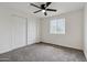 A cozy bedroom featuring plush gray carpeting and a ceiling fan for added comfort at 8132 W Earll Dr, Phoenix, AZ 85033