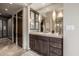 Bathroom vanity features dark wood cabinets, a large mirror, decorative lighting, and a sleek countertop at 11935 E Casitas Del Rio Dr, Scottsdale, AZ 85255