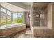 Bathroom with a soaking tub, walk-in shower, desert views, and natural stone floors for a spa-like experience at 11935 E Casitas Del Rio Dr, Scottsdale, AZ 85255