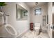 Well-lit bathroom with a toilet, urinal, mirror, and a small window adding natural light at 11935 E Casitas Del Rio Dr, Scottsdale, AZ 85255