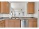 Kitchen features a stainless steel dishwasher, sink, wood cabinets and a passthrough to the living room at 1316 E Spencer St, Casa Grande, AZ 85122