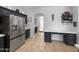 Elegant kitchen with a desk, stainless steel refrigerator, dark cabinets, and an arched entry at 13637 W Port Royale Ln, Surprise, AZ 85379