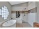 Bright bathroom featuring a soaking tub and glass enclosed shower with white and tan tiling at 1405 W Caribbean Ln, Phoenix, AZ 85023
