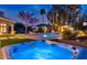 Outdoor jacuzzi and pool area illuminated by night lights and palm trees at 1405 W Caribbean Ln, Phoenix, AZ 85023