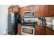Close-up of stainless steel oven and black refrigerator with granite countertops and wooden cabinets at 15024 N 142Nd Ln, Surprise, AZ 85379