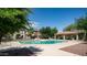 Community pool and shaded structure with seating, surrounded by lush trees and landscaping at 15024 N 142Nd Ln, Surprise, AZ 85379