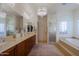 This primary bath offers dual sinks, granite countertops, walk-in shower, and soaking tub with tile flooring at 15954 W Sheila Ln, Goodyear, AZ 85395
