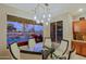 Dining area features a glass top table, chairs, modern chandelier, and views of the backyard, pool, and lake at 15954 W Sheila Ln, Goodyear, AZ 85395