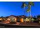 Inviting home exterior at twilight with a three-car garage, arched entrance, and lush, mature landscaping at 15954 W Sheila Ln, Goodyear, AZ 85395