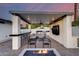 Inviting covered patio with a modern outdoor kitchen, stylish seating, and cozy fire pit for year-round enjoyment at 1609 W State Ave, Phoenix, AZ 85021