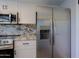 Stainless steel refrigerator and microwave in a remodeled kitchen with granite countertops and white cabinets at 16256 N 64Th Pl, Scottsdale, AZ 85254